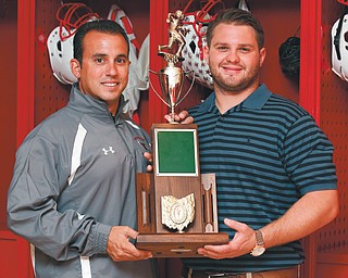 Cardinal Mooney football coach P.J. Fecko, left, and former two-way lineman Jon Italiano hold the Cardinals’ 2004 Division IV state championship trophy. Winning that title was the end of an emotional run by Cardinal Mooney’s players and coaching staff .
