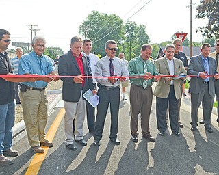 Tony Pannunzio, left, John Pannunzio, Struthers Mayor Terry Stocker, Rob Donham, John Getchey, Patrick Ginnetti, Tom Costello, Brad Calhoun, Rob Shenal and Matt Burger cut the ribbon at Wednesday’s ceremony opening the new roundabout at Mathews and Sheridan roads. Officials from Mahoning County, Poland and Boardman townships, Struthers and businesses involved in the project were present at the ceremony, as well as dozens of residents of the neighborhood.