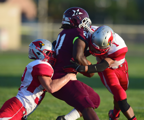 BOARDMAN, OHIO - AUGUST 29, 2014: Running back Benji Roberts #21 of Boardman is tackled by linebacker J.D. Matsko #32 and defensive back Micheal Ballentine #1 of Mentor during the 1st quarter of Friday nights OHSAA football game at Boardman Spartans Stadium. (Photo by David Dermer/Youngstown Vindicator)