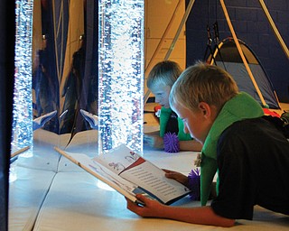 Colorful lights that change help to soothe Nolan Mickey as he reads a book in the sensory room in Austintown Elementary School. The room was not originally in the plans for the new building, district officials said, but once the space was available, the district bought equipment and opened it this school year.