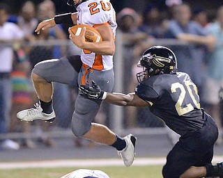 Jeff Lange | The Vindicator  Victor Williams, quarterback for Howland leaps over teammate Jordan Radich as he evades the tackle of Harding line backer Thad McCollough in the third quarter at Mollenkopf Stadium in Warren.