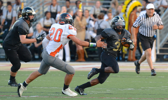 Jeff Lange | The Vindicator  Harding's Elijah Cofield (right) rushes to the sideline past Howland defender Victor Williams (20). Harding's Parker Stanislaw trails the play from the left.