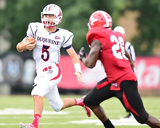 YOUNGSTOWN, OHIO - SEPTEMBER 6, 2014: Quarterback Dillon Buechel #5 of Duquesne runs away from defender Jameel Smith #26 of YSU during the 4th quarter of Saturday afternoon game at Stambaugh Stadium. YSU won 34-23. (Photo by David Dermer/Youngstown Vindicator)