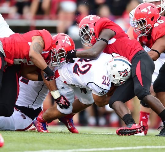YOUNGSTOWN, OHIO - SEPTEMBER 6, 2014: Running back Ryan Ho #22 of Duquesne is tackled by defenders Tre' Moore #2 and Deion Hall #19 during the 4th quarter of Saturday afternoon game at Stambaugh Stadium. YSU won 34-23. (Photo by David Dermer/Youngstown Vindicator)