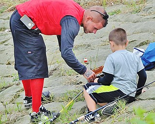 Jeff Lange | The Vindicator  Ron Trimble of Youngstown bends down to help his son R.J. Trimble untangle his fishing line during a morning of fishing at the Meander Reservoir, Saturday.