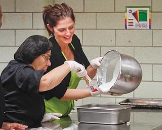Iris Pagan, left, and Heather Vanderbilt make fruit salad in the Gallagher’s Lunch Bucket kitchen in the basement of Oakhill Renaissance Place. The new lunch and breakfast cafe opened in late August.