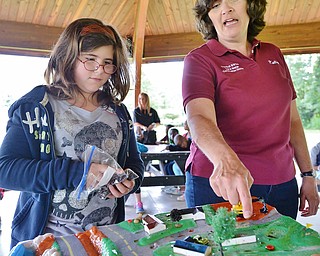 Jeff Lange | The Vindicator  Education Coordinator of the Trumbull Soil & Water Conservation District Kelly Hardval instructs Ashleigh Ellison 9 of McGuffey where to place 'manure' (chocolate chips) on the water table during Tuesday's demonstration at Perkins Park.