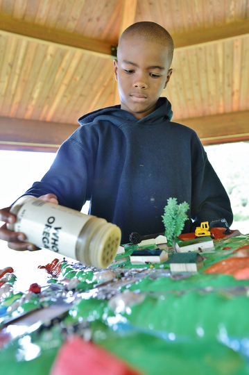 Jeff Lange | The Vindicator  Robert Williams Jr. 10 of McGuffey pours 'grass clippings' (oregano) on the streets of the water table during a simulation of water pollution, Tuesday morning at Perkins Park in Warren.