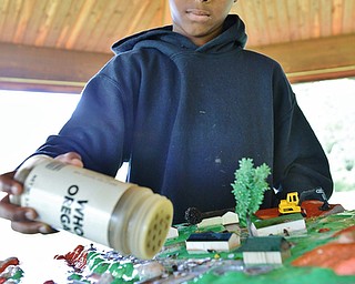 Jeff Lange | The Vindicator  Robert Williams Jr. 10 of McGuffey pours 'grass clippings' (oregano) on the streets of the water table during a simulation of water pollution, Tuesday morning at Perkins Park in Warren.