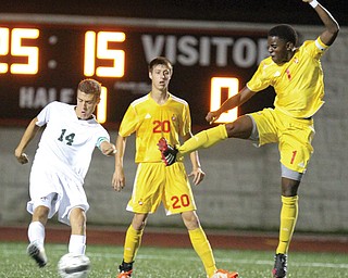 Ursuline’s John Hintz (14) kicks the ball past Mooney’s Christopher Perry (20) and Myles Harris (1) during their game Tuesday at Youngstown State University. The Cardinals shut out the Irish, 2-0.
