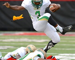 Jeff Lange | The Vindicator  Ursuline's Kimauni Johnson hurdles over a pile of Irish and Big Red players as a flag against the offense is thrown in the first quarter of their Friday night game at Harding Stadium.