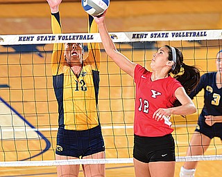 YSU’s Val Jeffery, right, bumps the ball over the net while Kent’s Bridget Wilhelm goes for the block during a match Tuesday at the MACC Center in Kent.