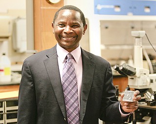        ROBERT K. YOSAY  | THE VINDICATOR..Tom Oder  holds a chip that is inside the plastic case...Tom Oder - Youngstown State University physics professor achieved a first for the university: a federal patent. behind him is President Jim Tressel ... -30-