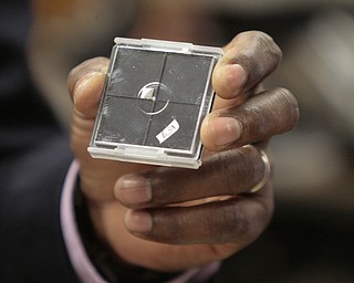        ROBERT K. YOSAY  | THE VINDICATOR..Tom Oder  holds a chip that is inside the plastic case..The chip is in the corner of the top left..Tom Oder - Youngstown State University physics professor achieved a first for the university: a federal patent. behind him is President Jim Tressel ... -30-