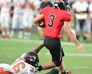 CANFIELD, OHIO - SEPTEMBER 19, 2014: Quarterback Drew Rogers #3 of Canfield slips a tackle by Elijah Thompkins #36 of Howland during the 1st half of Friday nights OHSAA football game at Canfield High School. (Photo by David Dermer/Youngstown Vindicator)