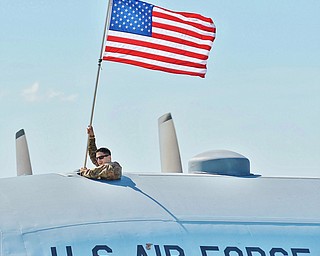 Jeff Lange | The Vindicator  Tech. Sergeant Ryan Wisniowski waves an American flag out of the top of the C-130 Hercules after landing on the airstrip at the Youngstown Air Reserve Station in Vienna. Wisniowski along with 60 other troops returned home Friday after a 120 day deployment to Southwest Asia.