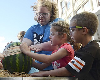 Katie Rickman | The Vindicator.Traci Manning of the Mahoning Valley Historical Society helps Nina Gordon, 8, or Poland and Ryan Grope, 5, also of Poland put rubber bands around a watermelon during Silly Science Sunday downtown Youngstown on Sunday, Sept. 21, 2014.