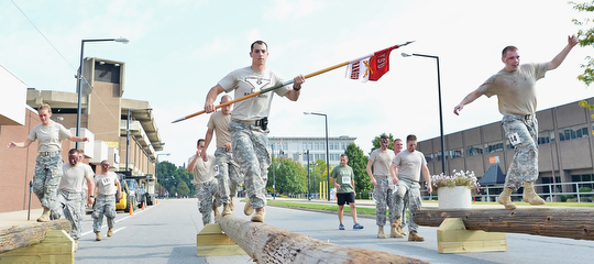 Jeff Lange | The Vindicator  Jared Hideg (center) carries the YSU Rangers guidon as he leads the YSU Army ROTC unit across the balance beams during Sunday's 1st annual Steelathon held in Youngstown.