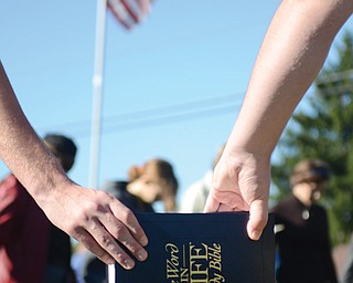 Two students at Victory Christian School in Liberty are linked by a Bible as they pray during a See You at the Pole prayer event Wednesday morning. The prayer event originated with a small group of students in Texas in 1990.