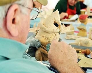 John O'Connor of Brookfield carves away at a wooden Grinch face at the Roundtable Carvers' display at the Red, White and True Festival held at Baird Brothers Fine Hardwood in Canfield, Saturday afternoon.