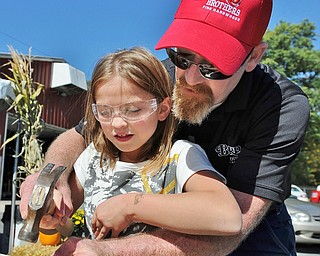 Baird Brothers employee J.R. Secrest assists Madison Aikens (8) in driving a nail as she builds a bird feeder during Saturday's festivities at Baird Brothers Fine Hardwood in Canfield. Madison is the daughter of Dan and Suzy Aikens of Salem.