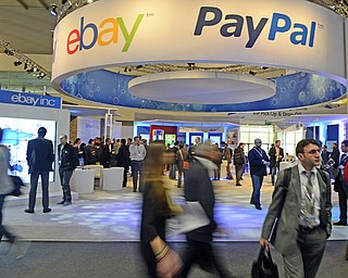 Attendees walk in front of a PayPal stand at the Mobile World Congress, the world’s largest mobile-phone trade show, in Barcelona, Spain. Online marketplace eBay Inc. announced Tuesday it is spinning off its payment business PayPal into a separate, publicly traded company by 2015.
