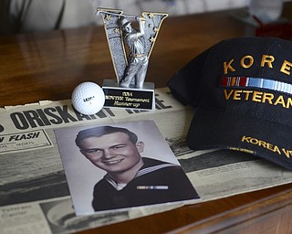 Katie Rickman | The Vindicator.Joe Skebo, a Korean War Veteran recently participated in  the "Tee Tournament in Iowa where he got a hole-in-one. Shown here is a trophy that he won there, the golf ball his used, his veteran hat, and an old photo of him resting on a newspaper clipping.
