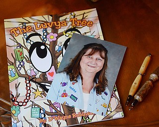 Katie Rickman | The Vindicator.A photo of Teresa Robinson rests on top of the book The Luvya Tree which is a children’s book that her husband D’Wayne wrote about her illness, to the right of the photo are pens that are made from the wood of the original Luvya Tree that once stood in the family’s living room during Teresa’s illness.