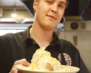 Katie Rickman | The Vindicator.Ross Fowler holds up one of the many hot foods served at at his restaurant The Kitchen Post which is located in Friends Specialty downtown Youngstown on Thursday, Oct. 9, 2014.