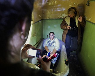 Jeff Lange | The Vindicator  Melissa Sanderbeck (center) of Newton Falls has her picture taken in an old bathroom in the brothel of the J.C. Thompson Building as Kimberly Mitchell of East Liverpool stands in the corner listening for ghosts, Saturday, Oct. 11th.