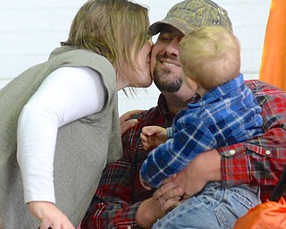 Jeff Lange | The Vindicator  Justin Reiter (with hat) is greeted with a kiss from his wife Holly at the leader's chair after his pumpkin weighed in at 1,106 pounds as his 22 month old son Tatum looks on, Saturday morning at Parks Garden Center in Green.