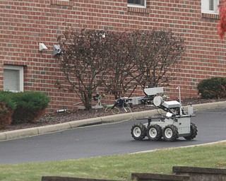        ROBERT K. YOSAY  | THE VINDICATOR..The Bombs Squad remote vehicle works the area where the bomb was noticed.( it was between the bushes)..The Youngstown Police Dept  bomb squad set off what appeared to be a pipe bomb outside a broken window at the Betras, Harshman and Kopp law office in Canfield on Seville Dr...that ended up not being explosive....-30-