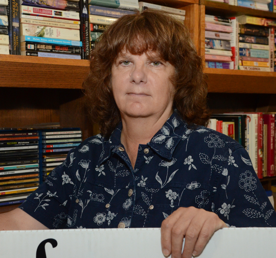 Katie Rickman | The Vindicator.Bonnie Viele, treasurer of Friends of the Library stands behind the sign that will hang in front of Hubbard Library during the book sale Oct. 22-Oct. 25, 2014. Viele along with many Friends of the Library volunteers meet Thursday mornings to sort through thousands of donated books at the Hubbard Public Library.