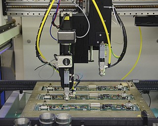 Katie Rickman | The Vindicator.A polyurethane conformal coding is sprayed onto a piece at the altronic Hoerbiger Engine Solutions facility on Thursday, Oct. 16, 2014.