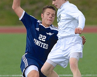 Jeff Lange | The Vindicator  United's Andrew Williams (22) slides to steal the ball away from Ursuline's Brendan Faloon during Saturday's soccer matchup at YSU.