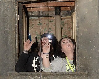 Thomas Hull and Melissa Sanderbeck peer out of a window inside the J.C. Thompson Building in East Liverpool. The two are part of a paranormal investigation hosted by Dark Shadow Ghost Tours.