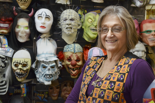 Katie Rickman | The Vindicator.Shirley James, owner of Ward Costumes Shoppe in Niles poses for a photo in front a wall full of masks in the shop on Monday, Oct. 20, 2014.