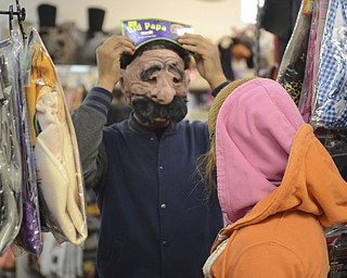 Katie Rickman | The Vindicator.Rico Rodrigues of Niles tries on a mask for Mariah Cicconi of Struthers at Ward Costume Shoppe in Niles on Monday, Oct. 20, 2014.