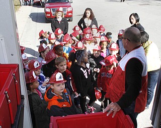        ROBERT K. YOSAY  | THE VINDICATOR..Gary Offerdahl with Red Cross Disaster Services shows students the equipment specifically  food boxes.....Kindergarten students from  E J BLOTT in Liberty head out with red fire hats from Gibson Insurance who sponsored the event with the Red Cross and  Liberty FD ...-30-