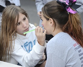 Katie Rickman | The Vindicator.Jenna Whited, 13, of Struthers (on left) who is a PANDA volunteer paints the cheek of Sydney Sarget, 13, also of Struthers during the tailgate party at Struthers Middle School on Wednesday, Oct. 29, 2014.