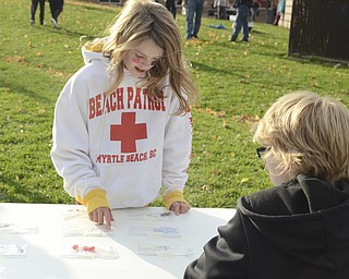Katie Rickman | The Vindicator.Rocksan Hampton, 11 (on left) plays a game at the PANDA Leadership Club table where student volunteer Anthony Bennett, 14, explains the guessing game during the tailgating party at Struthers Middle School on Wednesday, Oct. 29, 2014.