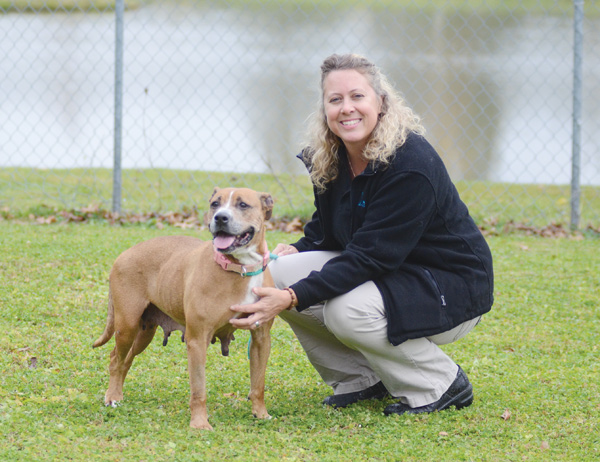 Kerry Pettit, director of operations at the Trumbull County Animal Welfare League, poses with Cinnamon, a 6-year-old boxer mix who is up for adoption, as she takes a break from playing in one of the Bark Parks.