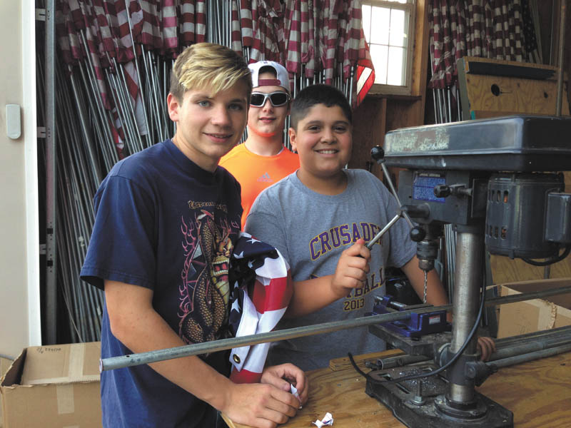 Boy Scouts with Troop 22, based at St. Christine Church, help place flags around the neighborhoods of the City of Canfield and Canfield Township with the Rotary Club of Canfield. The club sells memberships for the “Fly the Flag” program as a fundraising project. The money goes to Rotary projects on local and international levels. Above, the Scouts also help Rotarians prepare the flags for display. The task starts with drilling holes into the poles and then attaching the new flags. Accomplishing that work are, from left, Alex Mazon, Kyle O’Brien and Joey Nacarato. SPECIAL TO THE VINDICATOR