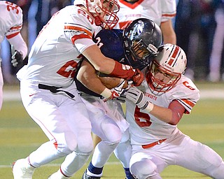 Jeff Lange | The Vindicator  Falcons' running back Tyler Hewlett (center) is sandwiched by two Grizzlies Austin White (left) and Kyle Kemppel (right) during second half regional action in Austintown, Friday night.
