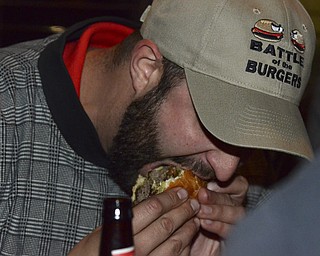 Katie Rickman | The Vindicator.James Chizmark of the Burger Guyz eats a burger at the Pour House Bar and Grill in Canfield on Wednesday, Nov. 5, 2014.