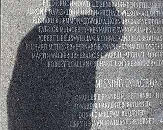 A veteran pays respects during the Reading of the Names portion of the ceremony at the Mahoning County Vietnam War memorial downtown. Roses placed at the monument honor the fallen soldiers.