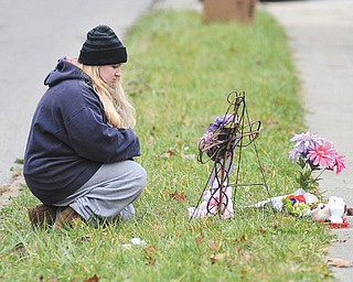 Jamie Bass, whose daughter was friends with East High School student Faith McCullough-Wooster, kneels beside a makeshift memorial for her on East High Avenue on Thursday. Faith was killed after she was run over by a city school bus Wednesday.