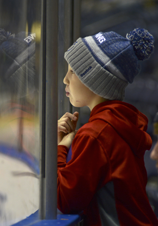 Katie Rickman | The Vindicator.Ryan Leasure, 9, of Niles leans against the plexiglass and watches the Phantoms play during the second period of the game against the Lincoln Stars at the Covelli Centre on Sunday, Nov. 16, 2014. Phantoms lost to the Lincoln Stars 3-4 in over time.