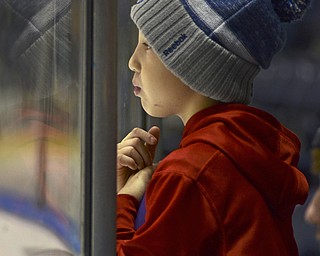 Katie Rickman | The Vindicator.Ryan Leasure, 9, of Niles leans against the plexiglass and watches the Phantoms play during the second period of the game against the Lincoln Stars at the Covelli Centre on Sunday, Nov. 16, 2014. Phantoms lost to the Lincoln Stars 3-4 in over time.