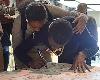 Katie Rickman | The  Vindicator.Taneja Williams, 16, hugs J’Saun Hall, 15 at East High School as he signs a poster for freshman Faith McCullough-Wooster the day after her death on Thursday, November 13, 2014.